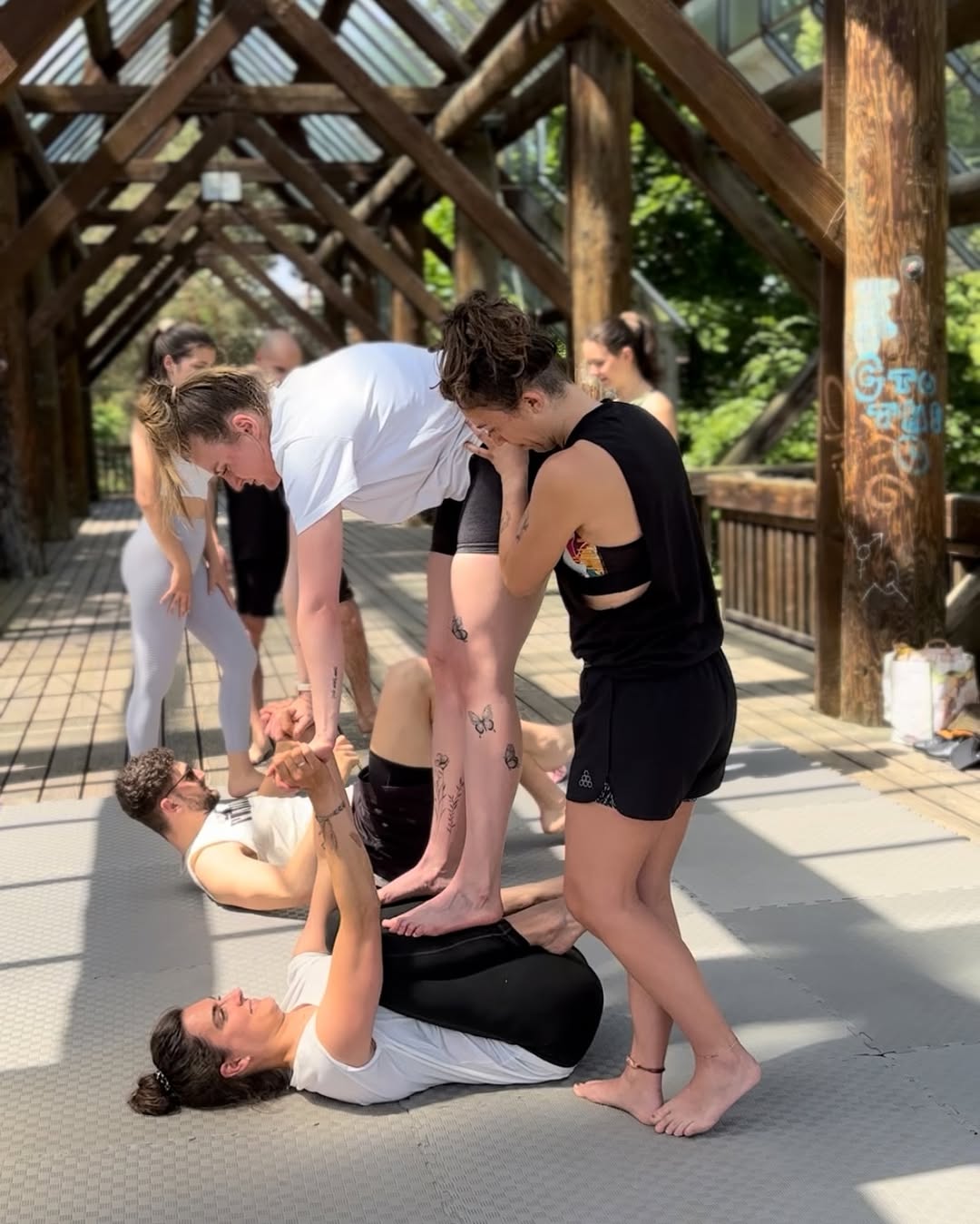 A flyer being spotted in an AcroYoga class at the Seepark Glashaus